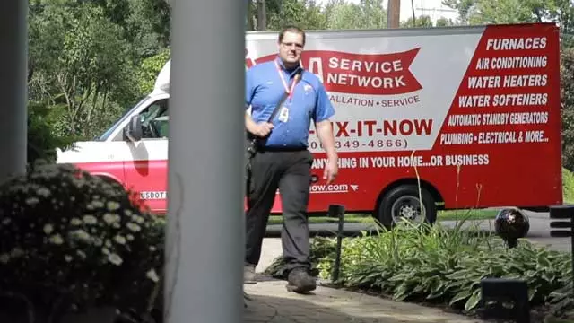 Technician walking up front path to a home, with AAA Service Network truck in background, in the driveway.