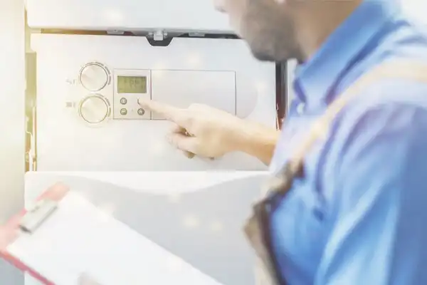 An AAA Service Network technician adjusts boiler controls, holding a clipboard to ensure top-quality service for our customers.